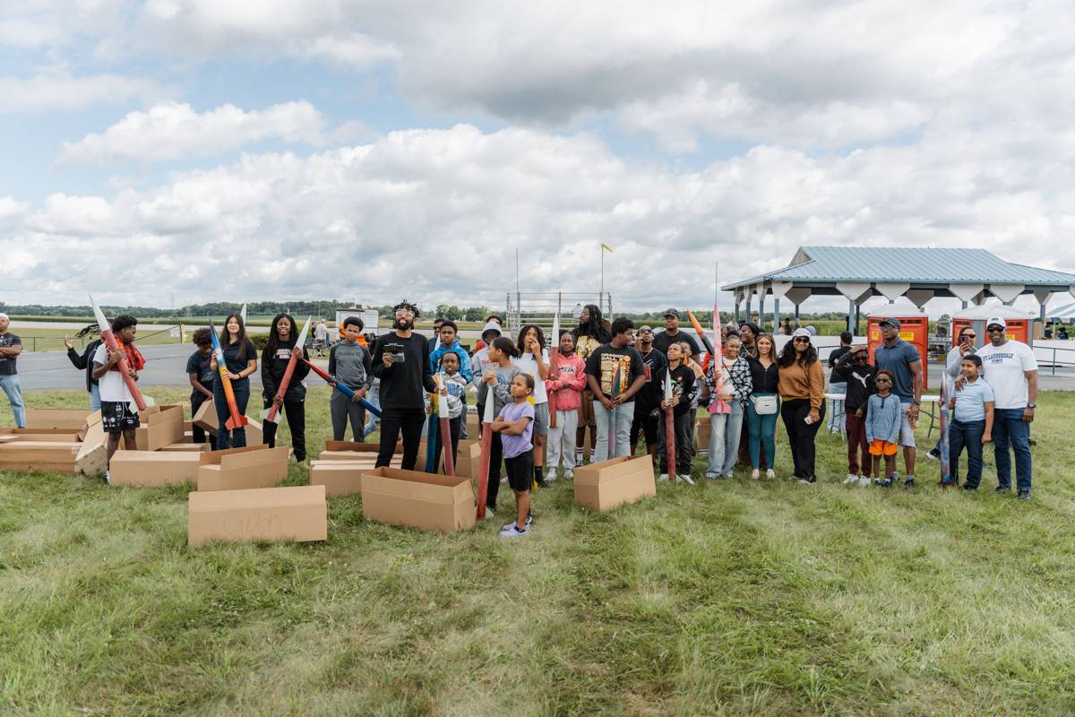 Bootcamp students, families and volunteers with their rockets at the launch field